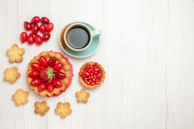 浆果俯瞰图：白色桌子上的小蛋糕 水果饼干和一杯茶饼干草莓水果