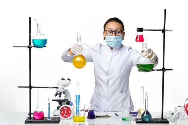 视图前视图穿着医疗服的女化学家 戴着面罩 在浅白色背景上工作 病毒化学实验室covidsplash工作面具医生