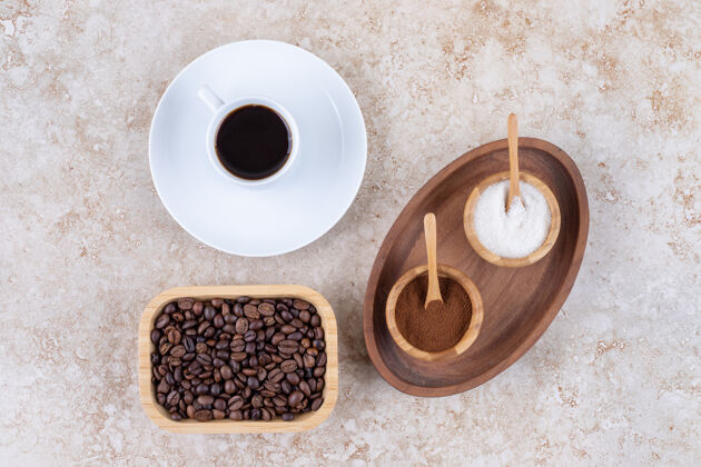 香味在一杯咖啡和一碗咖啡豆旁边放着几碗糖和磨碎的咖啡粉的小托盘茶碟碗粉末