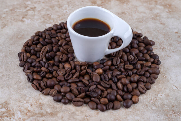 堆积整齐排列的咖啡豆堆围绕着一杯咖啡排列芳香