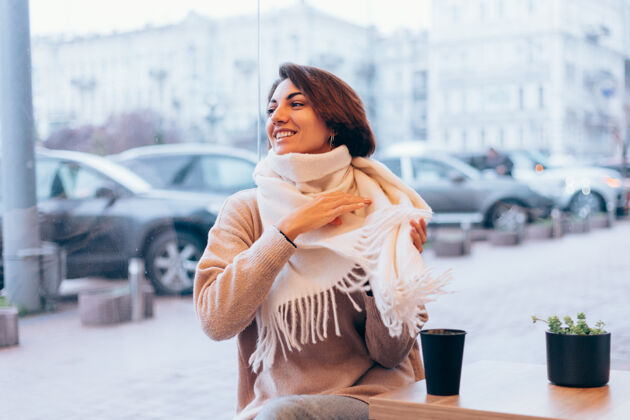 微笑一个女孩在舒适的咖啡馆里用一杯热咖啡取暖冬天羊毛冷