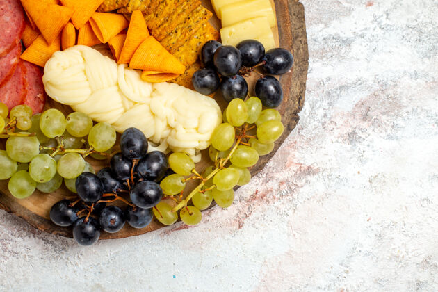水果顶视图不同的小吃cips香肠奶酪和新鲜葡萄在白色空间浆果葡萄藤不同