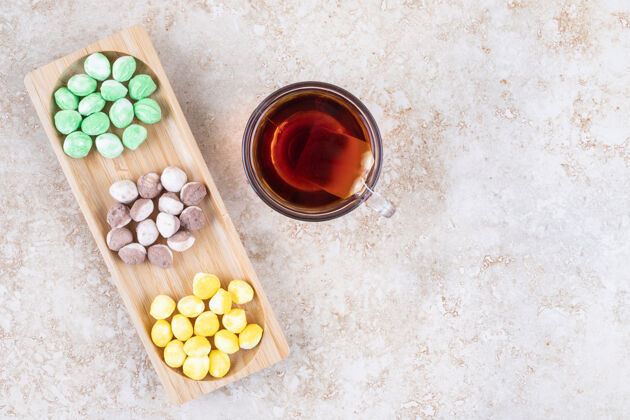 什锦一杯茶和各式各样的糖果装在一个小木托盘里茶美味小吃
