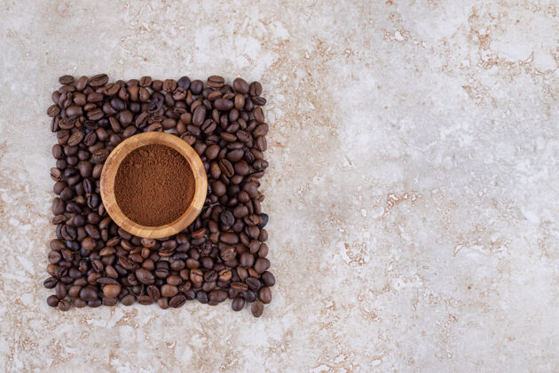 粉装着咖啡粉的小碗里围着一小堆咖啡豆咖啡豆