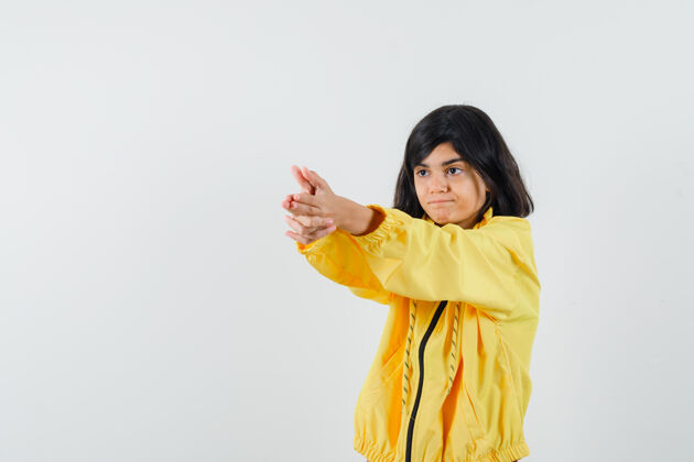 女性穿着黄色连帽衫的小女孩展示了持枪姿势 看起来很自信 正面视图动物脸欢呼