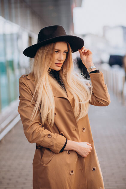 优雅戴着黑帽子 穿着米黄色外套的年轻漂亮女人走过商场长发米色外套购物日