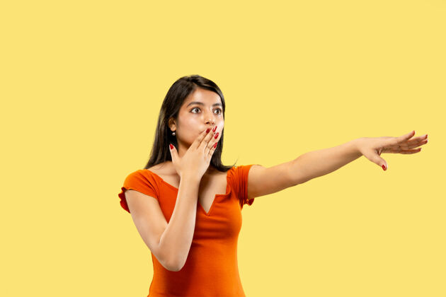 年轻美丽的女性半身肖像隔离在黄色的工作室背景上年轻感性的印度女人穿着衣服指着和展示消极的空间面部表情 人类情感的概念表情人头发