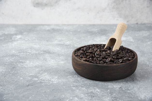 木制碗中烤咖啡与勺子大理石表面咖啡粒天然的香气