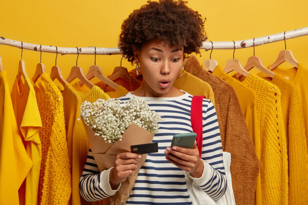 条纹卷发惊艳女人横拍使用现代手机 核对余额 持信用卡 上网购物客户包付款