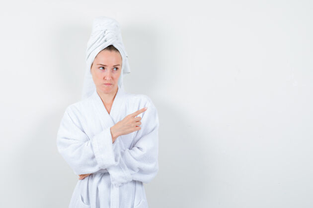 人画像中的年轻女子指着右上角的白色浴衣 毛巾和看犹豫的前视图毛巾模型黑发
