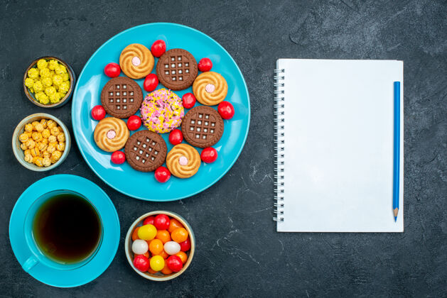 饼干顶视图不同的糖饼干与糖果和茶杯的灰色表面糖果糖甜茶饼干饼干柜台谷类食品糖果