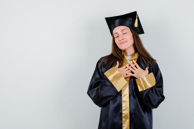 毕业女毕业生身着学院服 双手放在胸前 看起来很放松的正面照片学士肖像放松