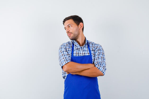 烹饪穿着蓝色围裙和衬衫的年轻男厨师厨师衬衫男士