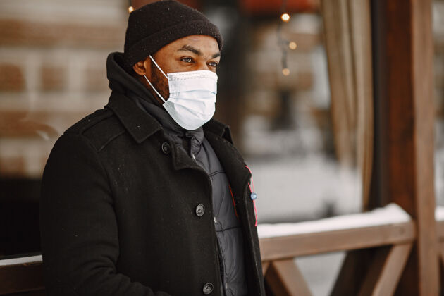 夹克冬天小镇上的男人穿黑外套的男人戴医用面罩的男人男性商业外面