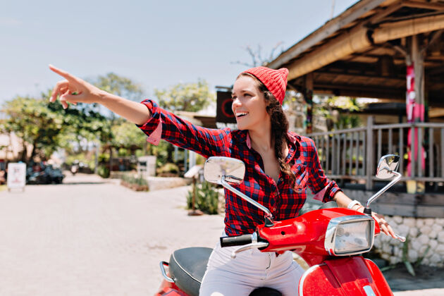 肖像在阳光明媚的日子里 穿着格子衬衫 粉色帽子和白色牛仔裤 骑着红色自行车在热带地区兜风的快乐美女海洋阳光旅游
