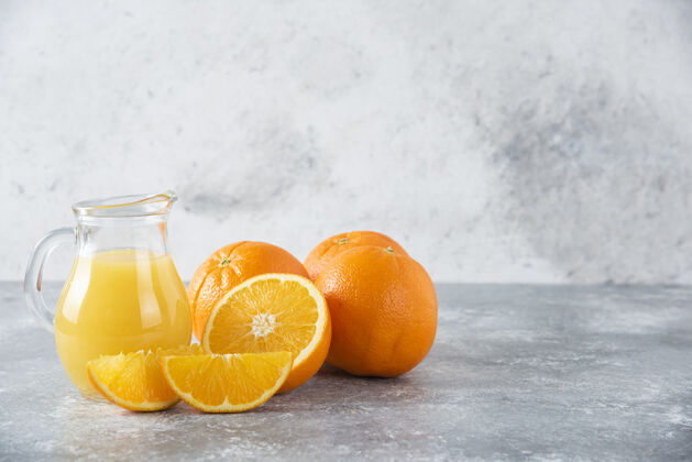 果汁石桌上放着一杯果汁和新鲜的橙子天然美味新鲜