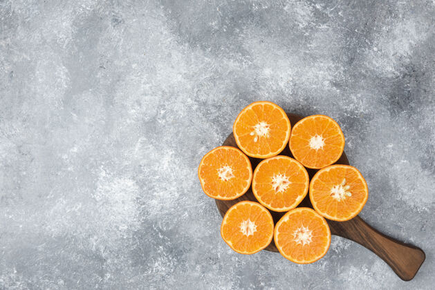新鲜石桌上放着一块木板 上面放着多汁的橙子片橘子自然成熟