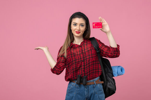 人正面图身穿红色衬衫的年轻女性手持银行卡 背景为粉色人类女性颜色年轻女性成人衬衫