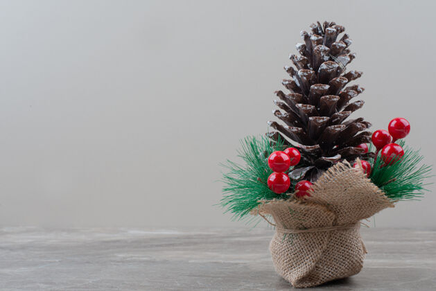 假日用冬青浆果和树枝装饰的松果放在大理石桌上冬天圆锥体树枝