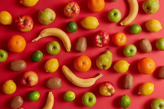 堆从果园采集的美味热带和国内水果红色背景的美味开胃香蕉 猕猴桃 苹果 梨和柠檬各种健康有益的天然产品平铺混合酸橙膳食