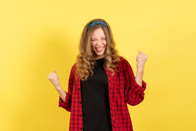 肖像正面图身着红色格子衬衫的年轻女性在黄色背景上摆出幸福的姿势人类情感色彩模特儿女人情感年轻女性衬衫