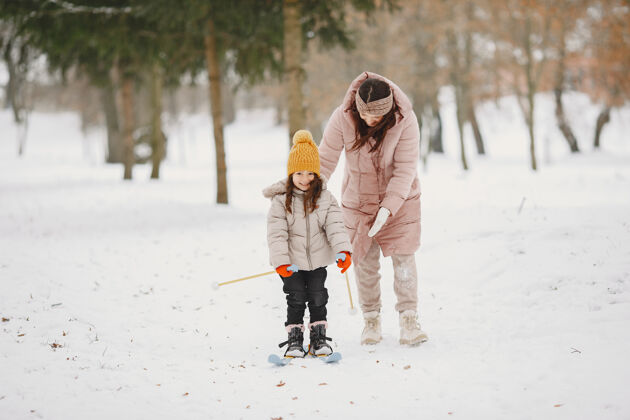 公园小女孩和妈妈一起越野滑雪寒冷假期年轻