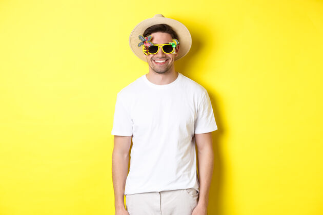 夏天旅游度假的概念轻松微笑的男人享受晚餐之旅 戴着墨镜和草帽 黄色背景表情男人成年人