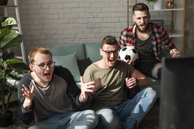 一起快乐的男性朋友看电视上的体育节目和足球同志电视水平
