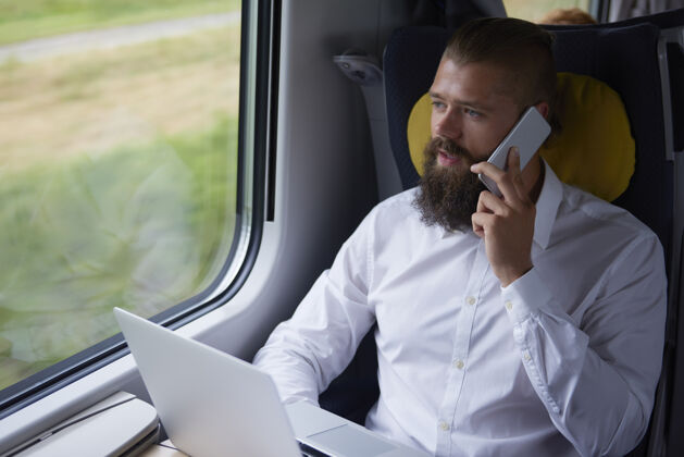 商务旅行年轻的商人在火车上用手机交谈火车沉思商业策略