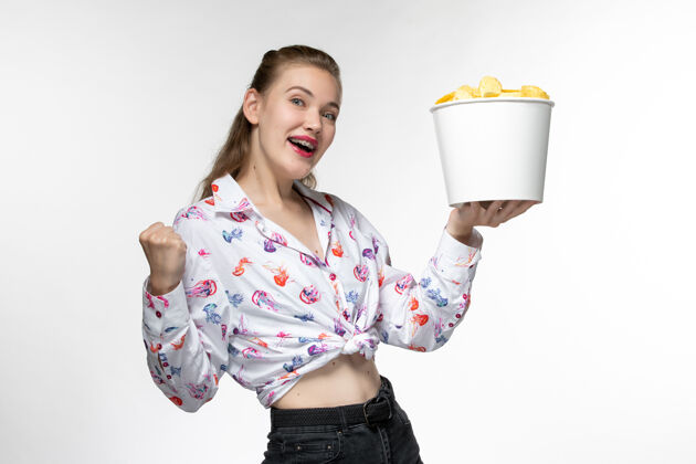 前面正面图：白色表面上拿着薯片的年轻女性手提篮电影电影土豆
