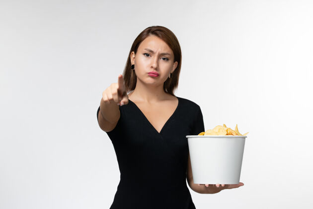 电影院正面图：年轻的女性拿着土豆片的篮子 在白色的表面上看电影剧院抱着漂亮