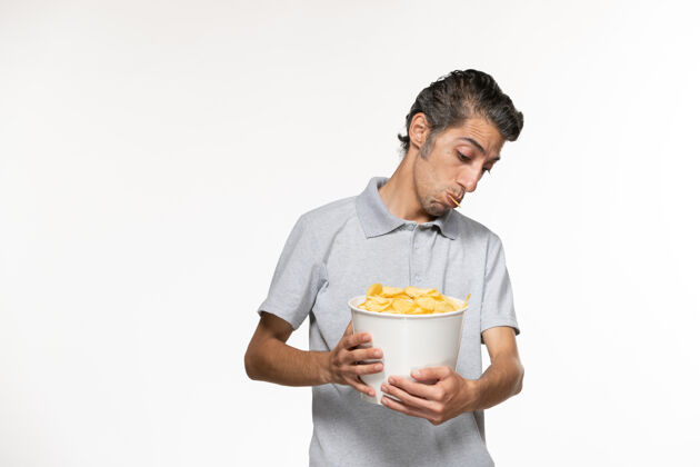 电影院正面图：白色表面上放着薯片的年轻男性手提篮篮子服务员土豆