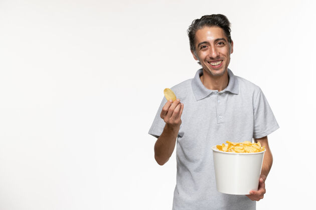 年轻的男性正面图：年轻男性手提篮 浅白色表面上放着薯片男孤独电影院