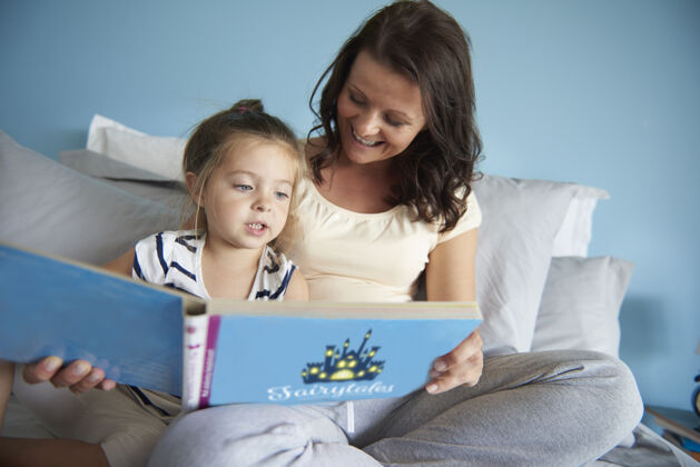 拥抱妈妈和女儿在读童话故事教育护理家庭生活