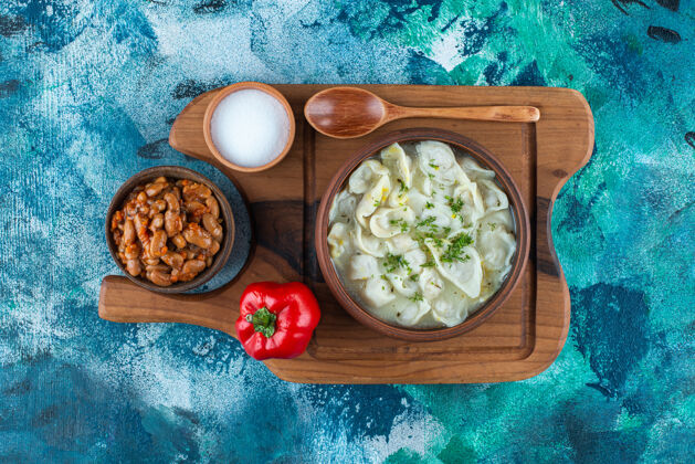 风味烤豆子 杜什巴拉 勺子 胡椒粉和盐在一块板上 在蓝色的背景上阿塞拜疆汤匙传统