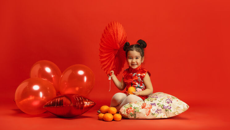 小红墙上穿着传统服装的亚洲可爱小女孩服装美丽快乐