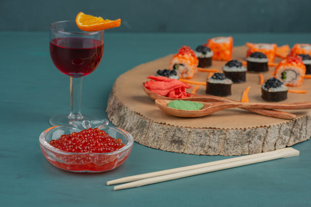 寿司把寿司 红鱼子酱和一杯红酒放在蓝色的桌子上鱼鱼子酱食物
