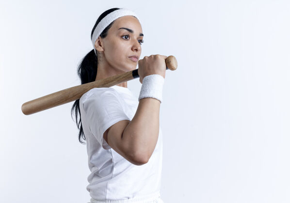 侧年轻自信的白人运动女性戴着头带和腕带站在一边 肩上拿着球棒 在空白处与复制空间隔离信心肩膀复制