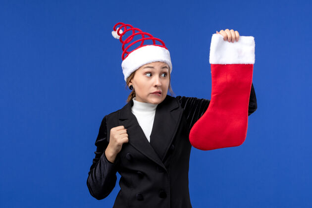 袜子正面图年轻的女性拿着红色的圣诞袜在蓝色的墙上过年职业持有工作