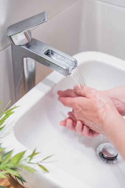 保护女性用肥皂和水洗手的垂直镜头健康浴室人
