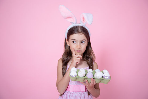 小有复活节兔子耳朵的小女孩 手里拿着一盘粉红色的鸡蛋托盘兔子鸡蛋