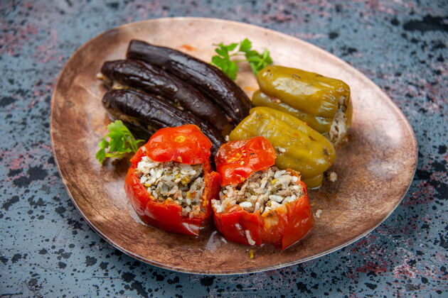 晚餐前视图茄子与煮熟的西红柿和甜椒与肉末填充在蓝色背景板内多尔玛里面菜背景