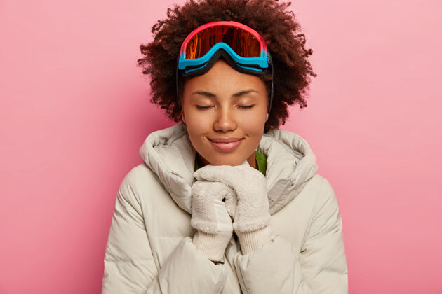 寒冷女滑雪者喜欢滑雪 穿着白色羽绒服 戴着白色软手套 手放在下巴下面滑雪者手套欢呼