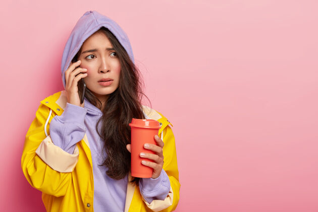交谈满脸红润 表情紧张的亚洲女人 通过智能手机给男友打电话 试图用外卖咖啡取暖担心设备手机