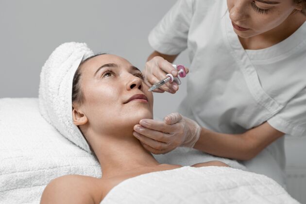 女人美容师为女性客户做填充物注射美容院美容治疗美容治疗