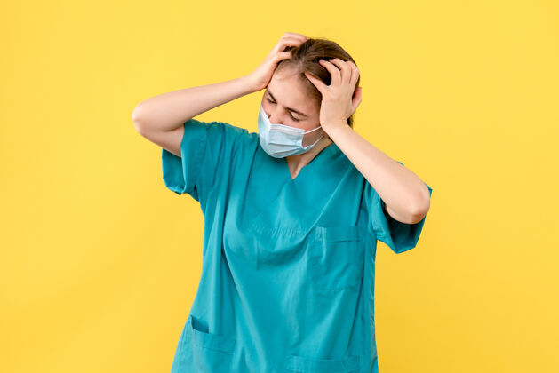 肖像正面图黄色背景上头痛的女医生-医院卫生大流行成人人医院