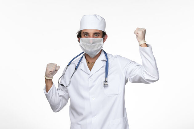 大流行正面图穿着医疗服的男医生戴着无菌口罩 以防白墙上的病毒传染专业人员听诊器疾病