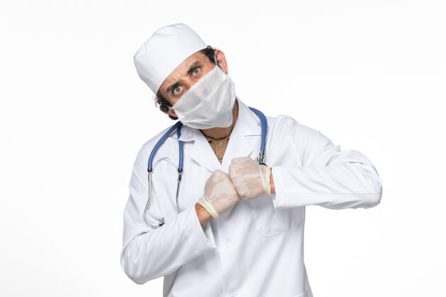 视图正面图：男医生穿着医疗服 戴着口罩 以防白墙病毒溅起冠状病毒大流行专业喷溅西装