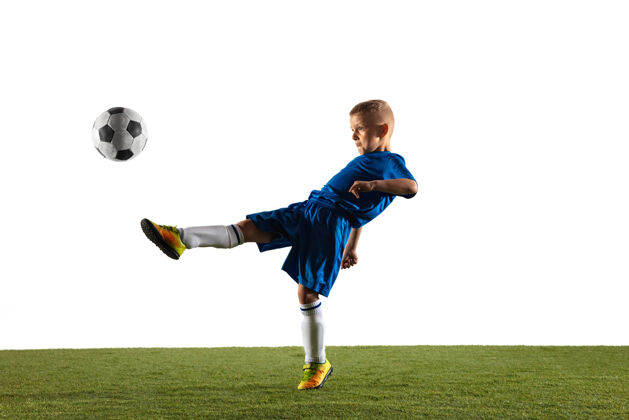 草地穿着运动服的足球运动员或足球运动员的小男孩 为了在白色场地上进球而用球假装或踢运动身体绿色