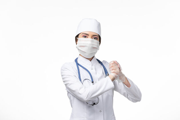 病毒正面图：女医生穿着白色无菌医疗服 戴着口罩 因为柯维德-在白色办公桌上摆姿势-柯维德病毒-大流行性疾病冠状病毒预防冠状病毒防护制服